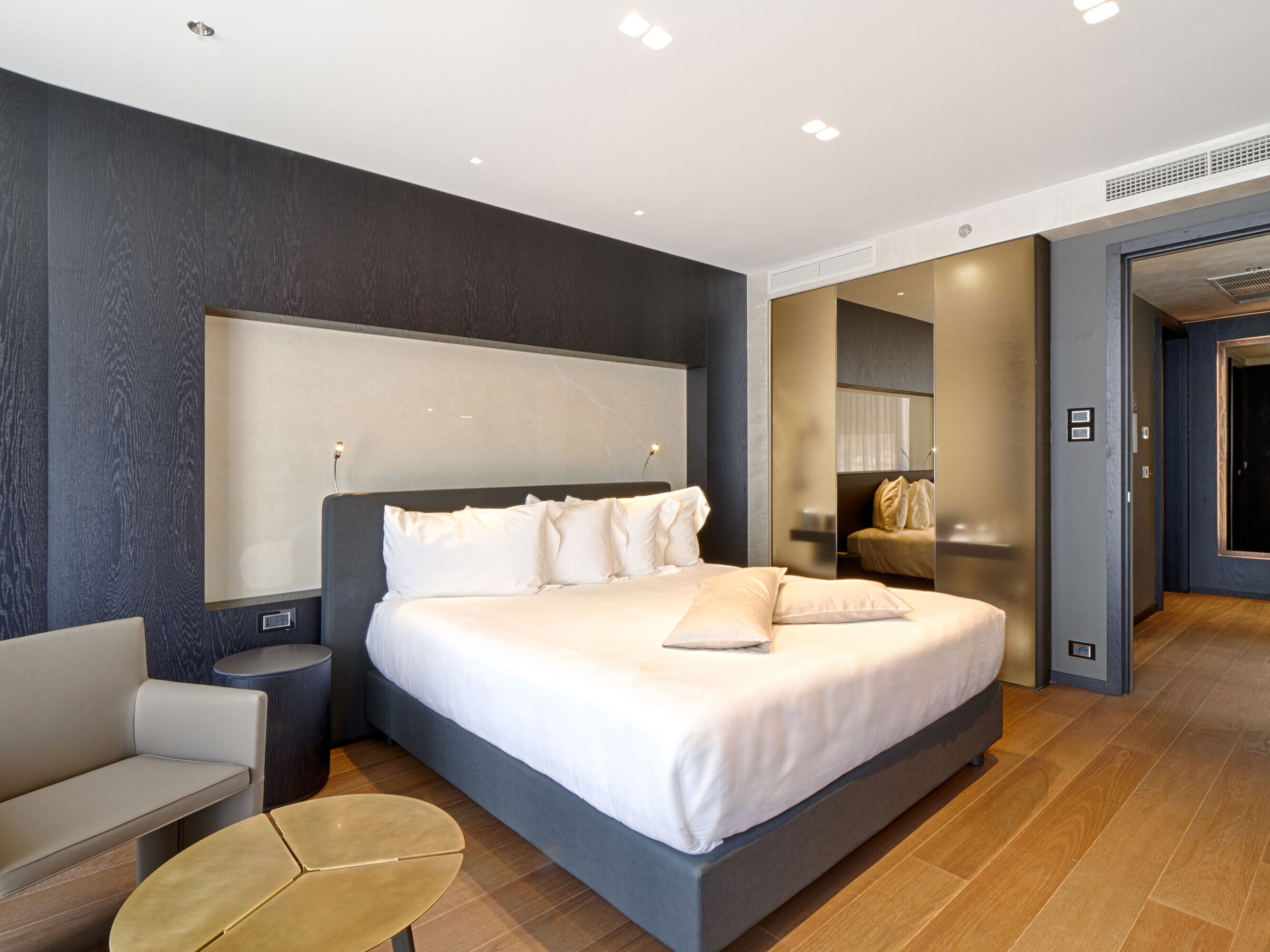 Modern hotel room with king-size bed, light wall niche and wooden floor at Maritim Hotel Plaza Tirana