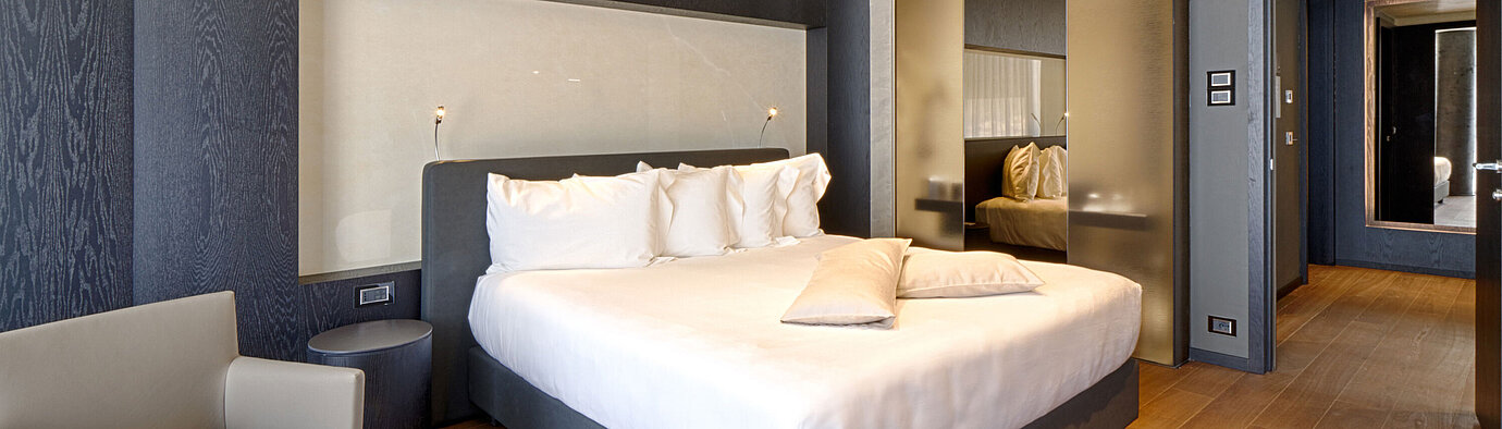 Modern hotel room with king-size bed, light wall niche and wooden floor at Maritim Hotel Plaza Tirana