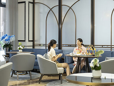 Two guests enjoying afternoon tea in a stylish hotel lounge with comfortable seating