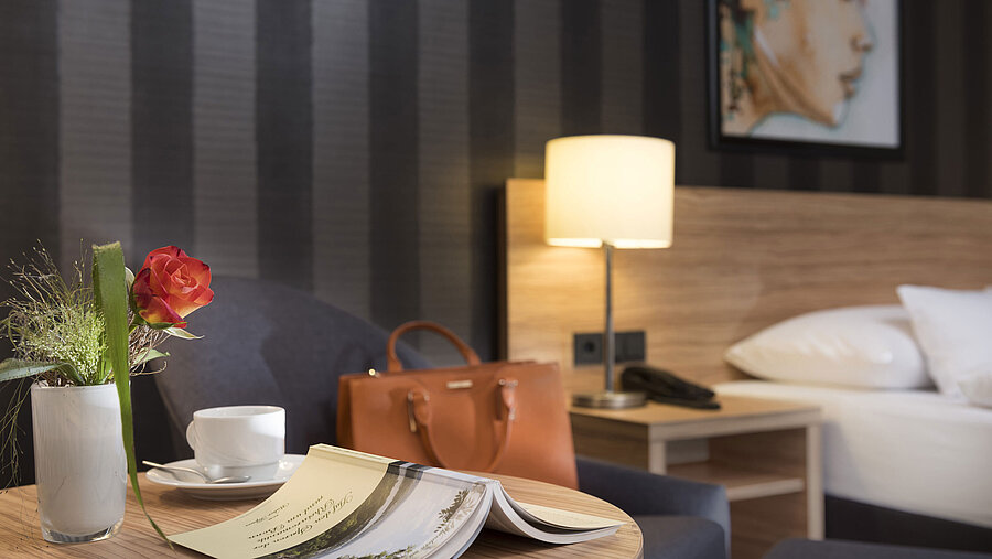 Stylish table decoration at Maritim Hotel Königswinter with rose, handbag, and cozy atmosphere.