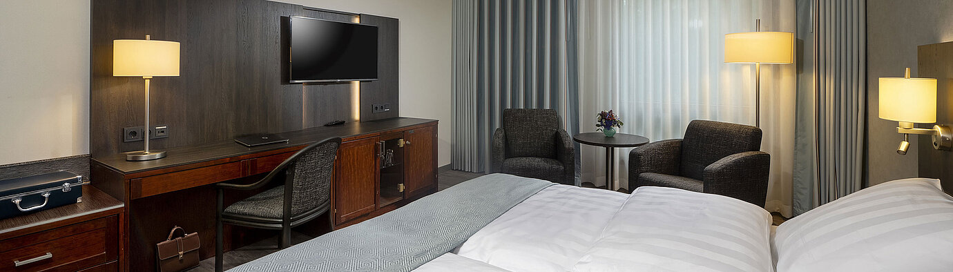 Elegant double room at Maritim Hotel Bremen with modern furnishings, comfortable beds, and a cozy seating area.