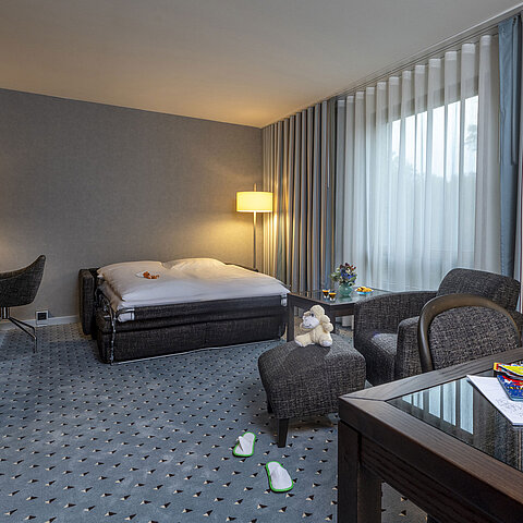 Family room at Maritim Hotel Bremen with sofa bed, toys, and a welcoming ambiance, perfect for a family stay.