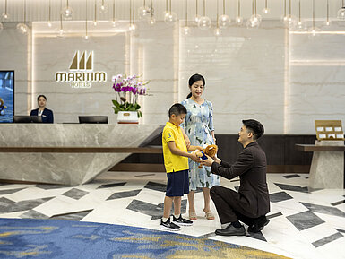 Hotel staff member welcoming a child and family with a plush toy at the Maritim Hotels reception