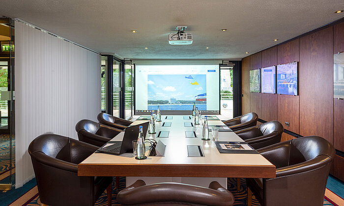 Conference room "Salon Fulda" at Maritim Hotel Timmendorfer Strand with conference table, leather chairs, and projector.