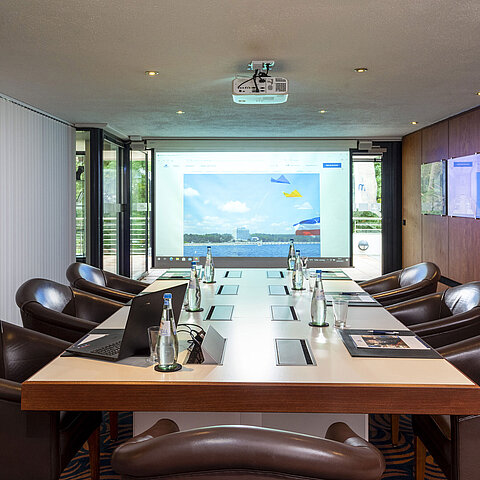 Conference room "Salon Fulda" at Maritim Hotel Timmendorfer Strand with conference table, leather chairs, and projector.