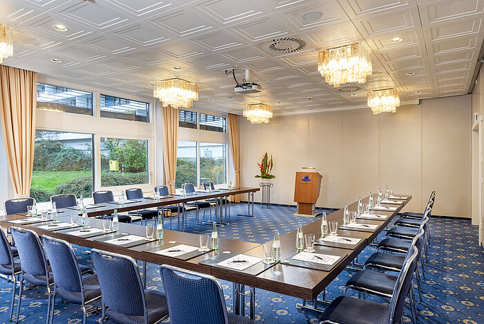 The Salon Lübeck in the Maritim Hotel Kiel, a modern conference room with U-shaped seating, large windows and chandeliers.