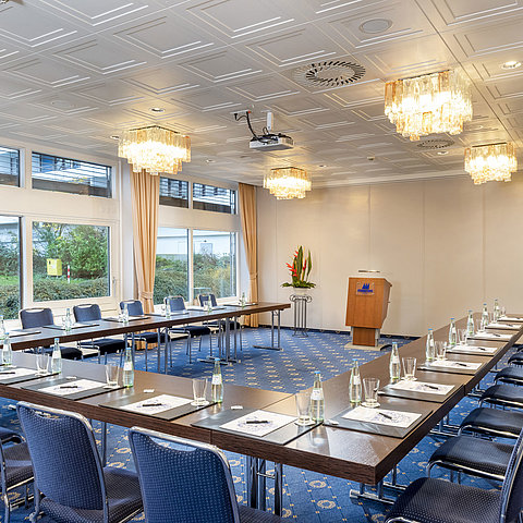 The Salon Lübeck in the Maritim Hotel Kiel, a modern conference room with U-shaped seating, large windows and chandeliers.