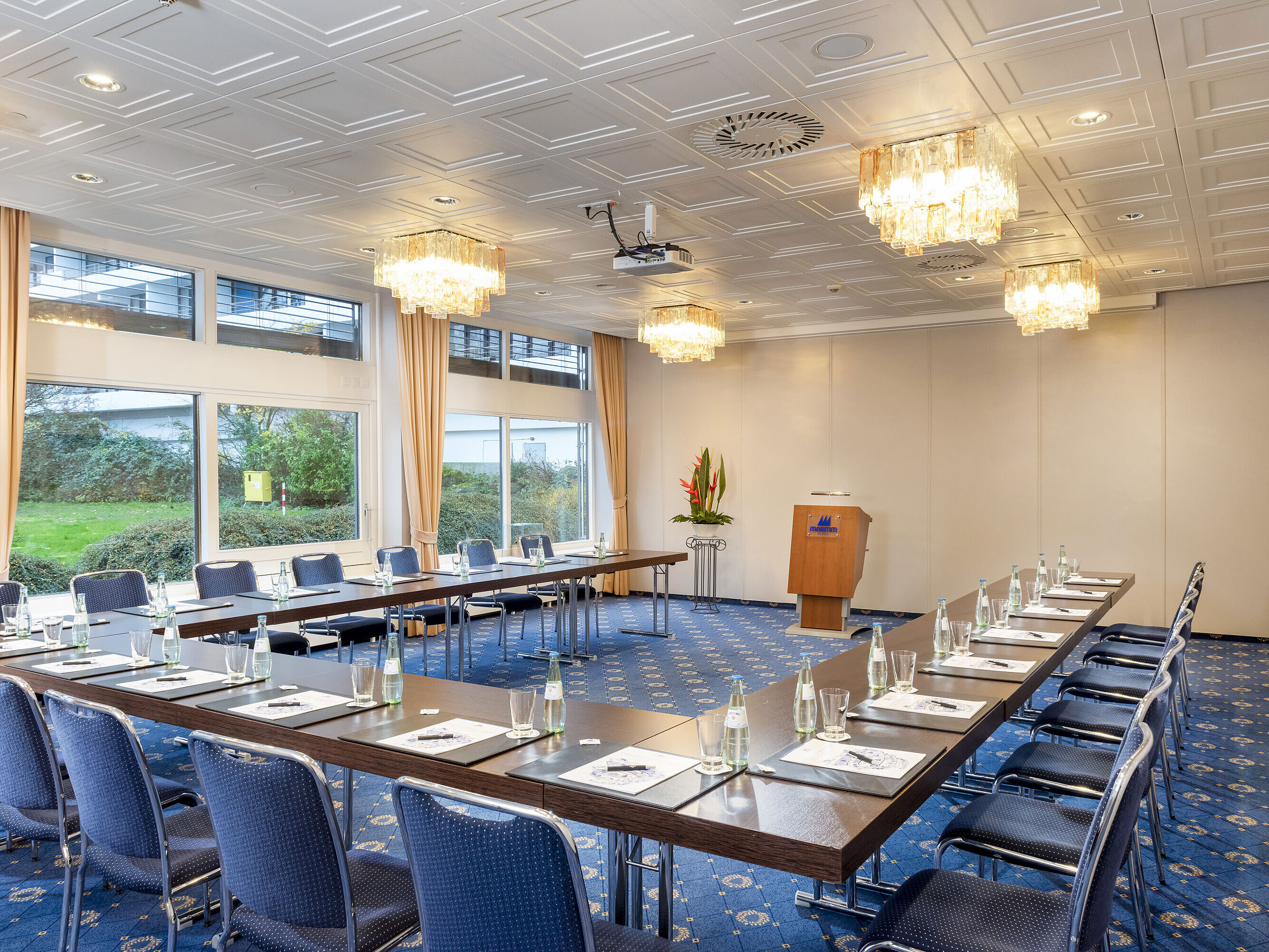 The Salon Lübeck in the Maritim Hotel Kiel, a modern conference room with U-shaped seating, large windows and chandeliers.