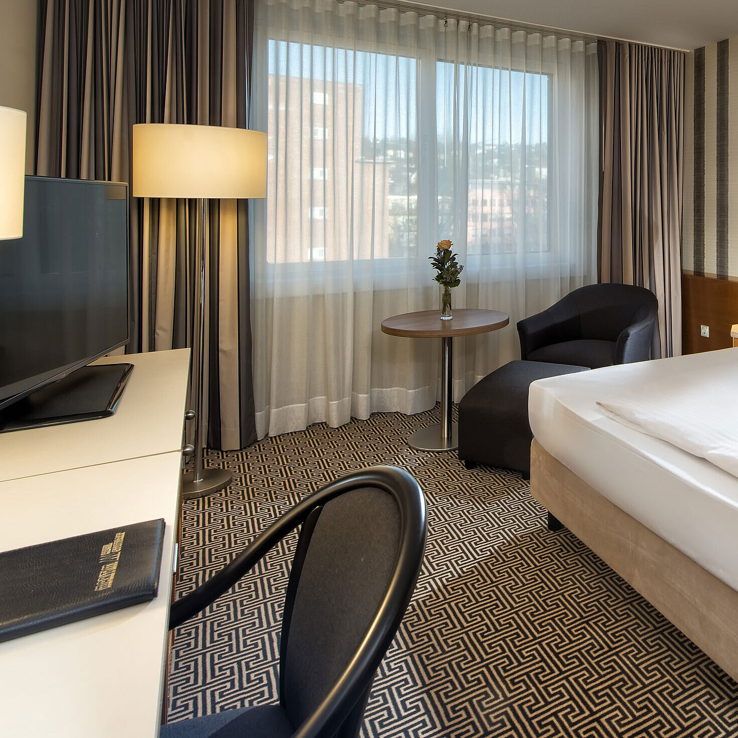 Modern single room with desk, large window and city view at Maritim Hotel Stuttgart