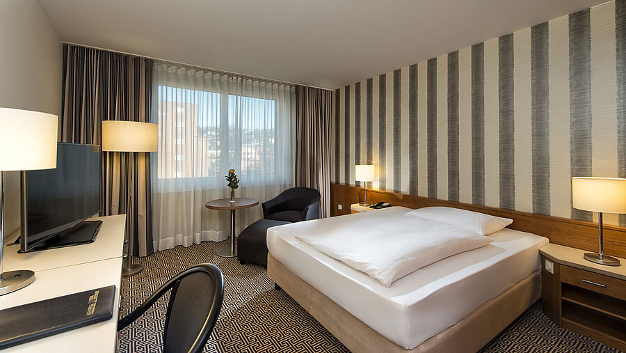 Modern single room with desk, large window and city view at Maritim Hotel Stuttgart