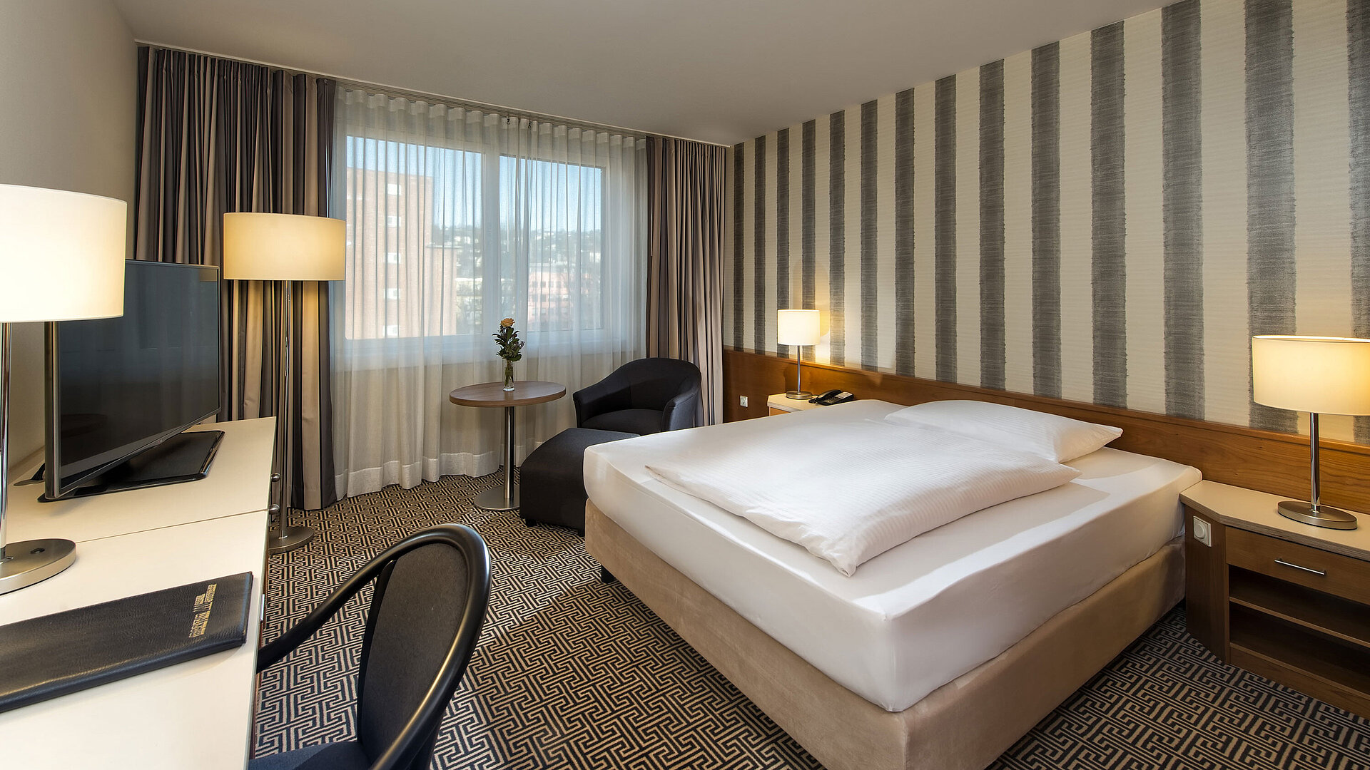Modern single room with desk, large window and city view at Maritim Hotel Stuttgart