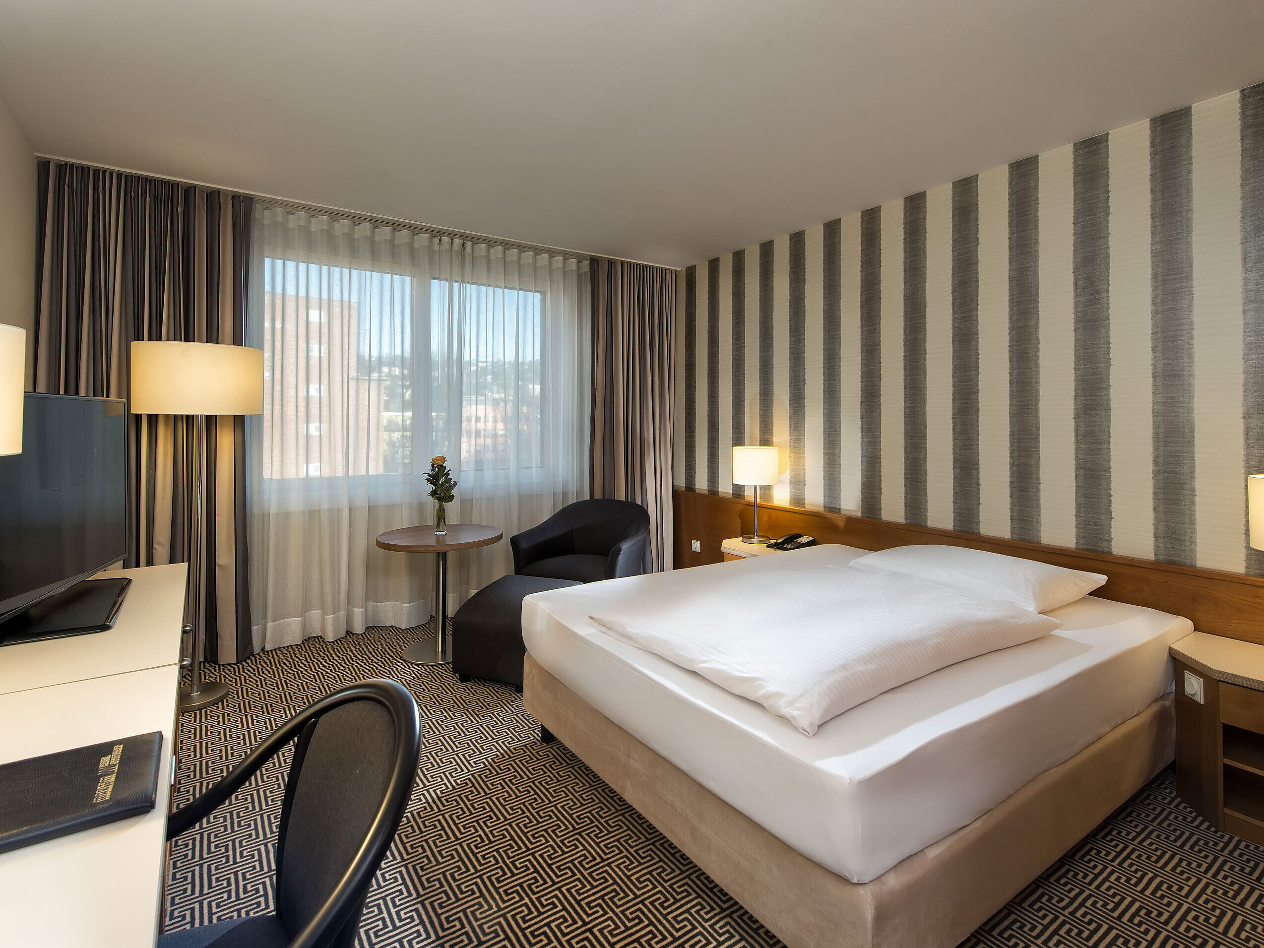 Modern single room with desk, large window and city view at Maritim Hotel Stuttgart