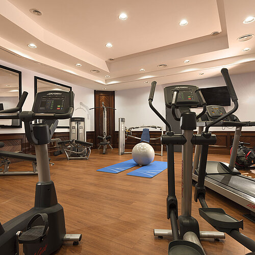 Modern gym with cardio equipment, weights and yoga mats at Maritim Hotel Ulm.