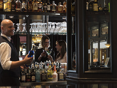 Piano bar Happy guests enjoying cocktails at the bar of Maritim Hotel Dresden, served by a friendly bartender.