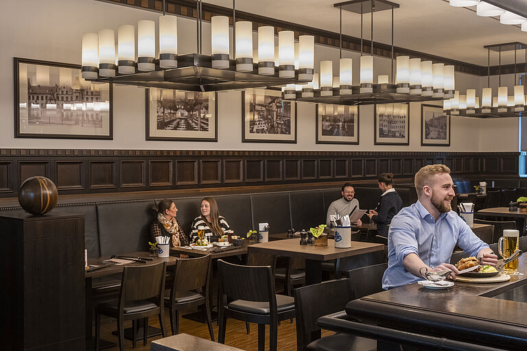 Guests enjoying meals in the cozy "Rheinische Stov" restaurant at Maritim Hotel Düsseldorf with stylish interior and ambiance.