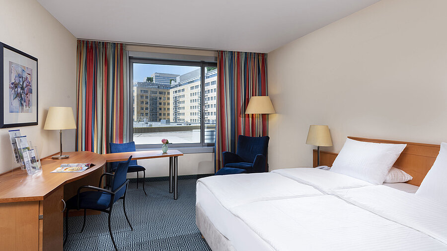 Classic room at Maritim Hotel Frankfurt with a cozy double bed, desk, and city view.