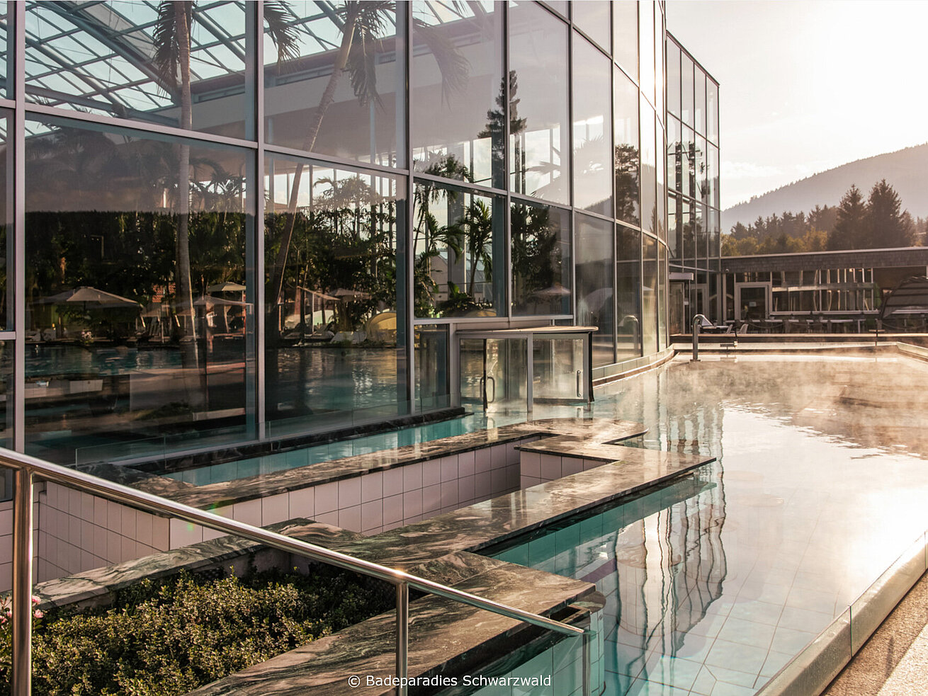 Modern spa building with outdoor pool and water features at sunset