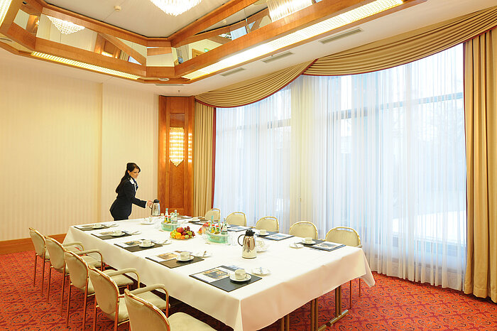 Elegant meeting room with natural light, set table, and warm ambiance at Maritim Hotel Magdeburg.
