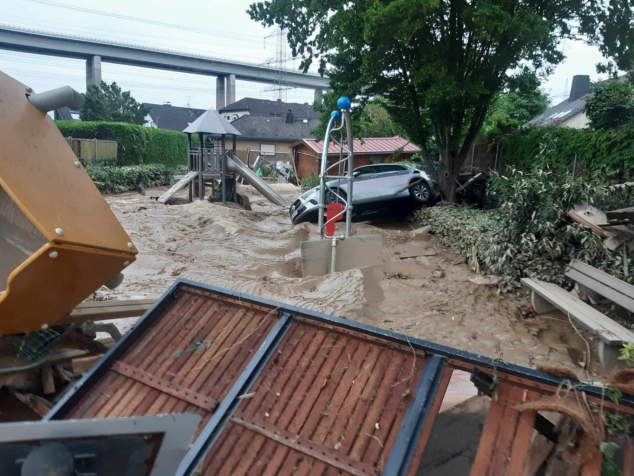 Flood damage at a playground Flooded playground with a damaged car and mud following severe flooding in a residential area