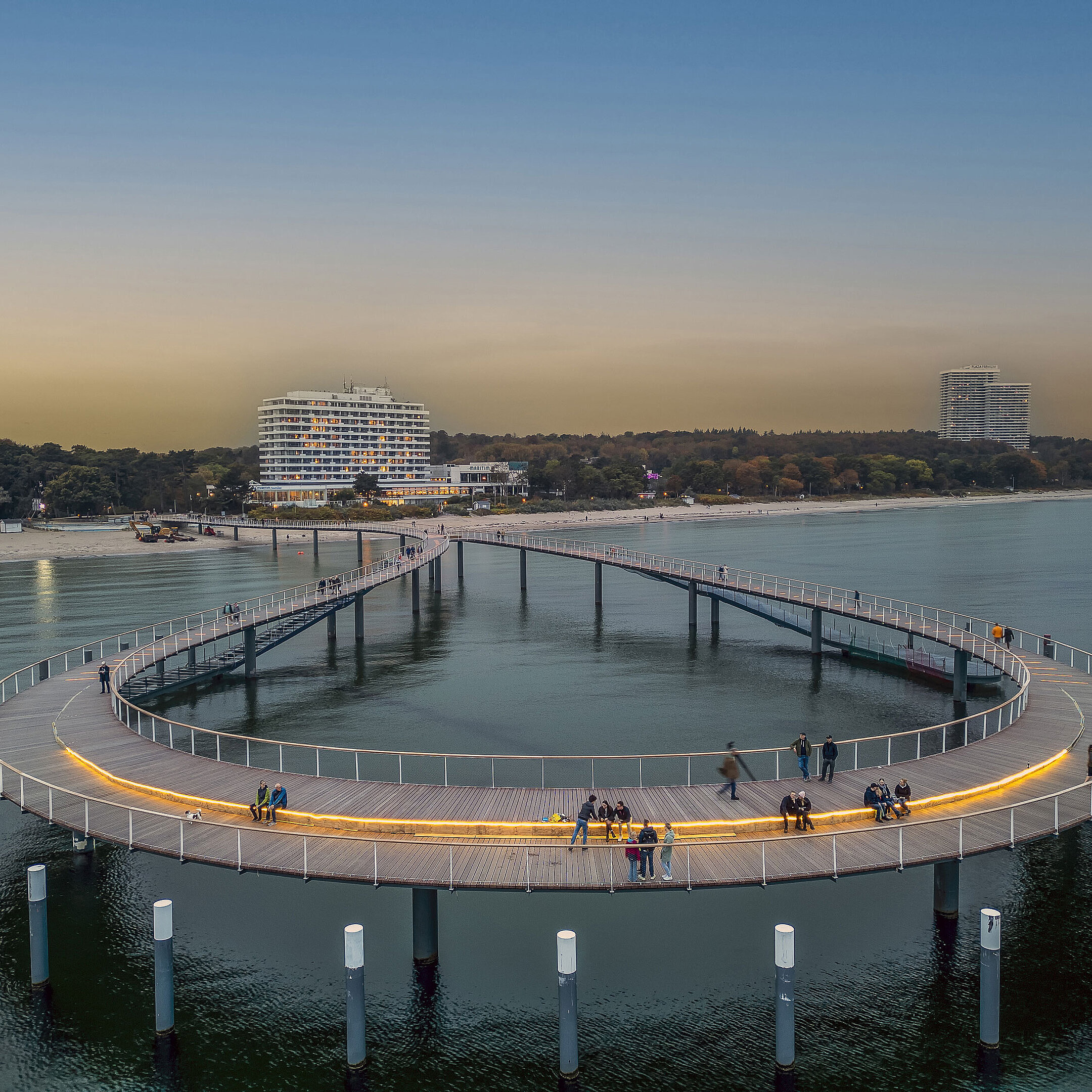 Illuminated pier at dusk in front of the Maritim Seehotel Timmendorfer Strand.