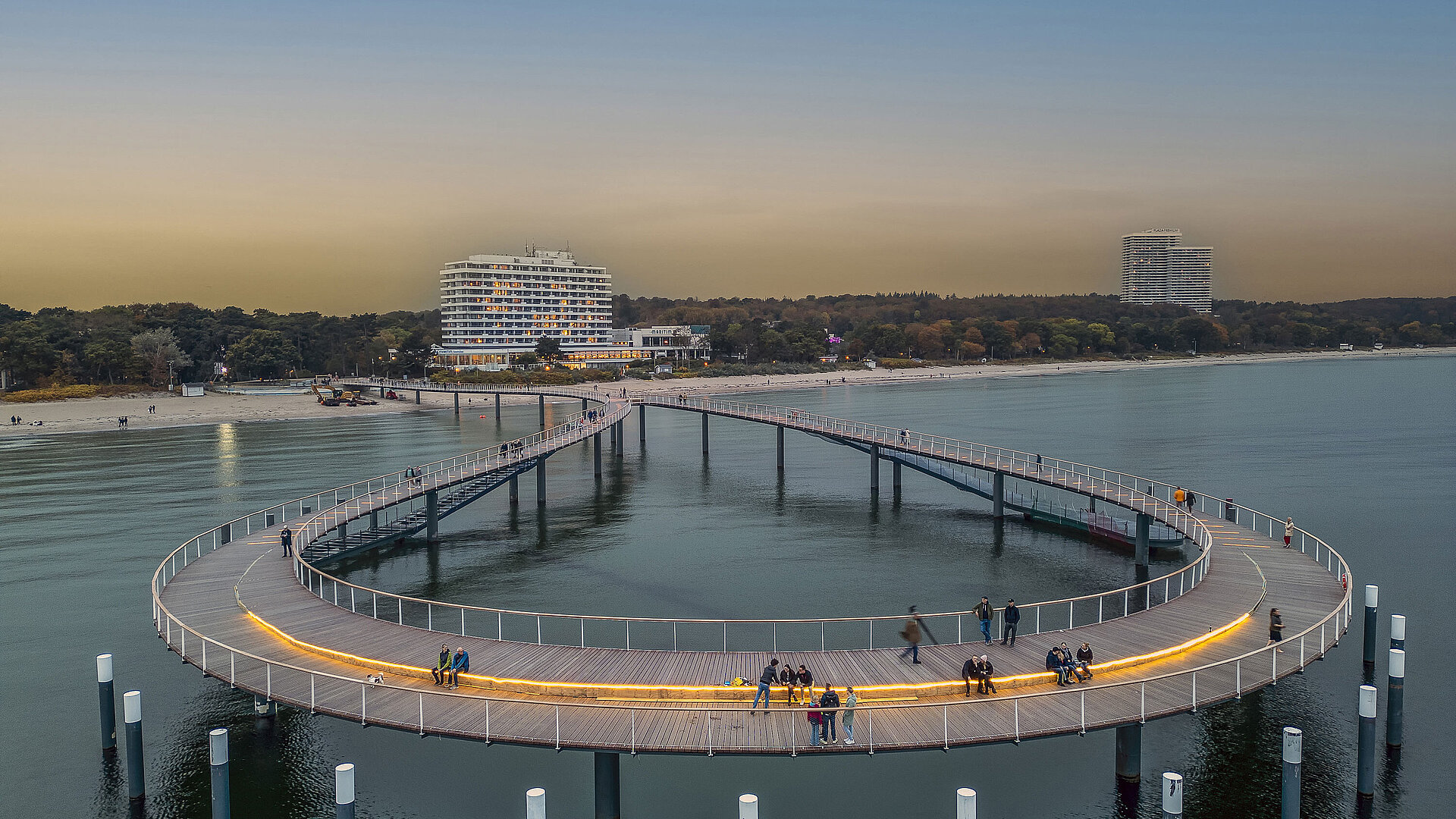 Illuminated pier at dusk in front of the Maritim Seehotel Timmendorfer Strand.
