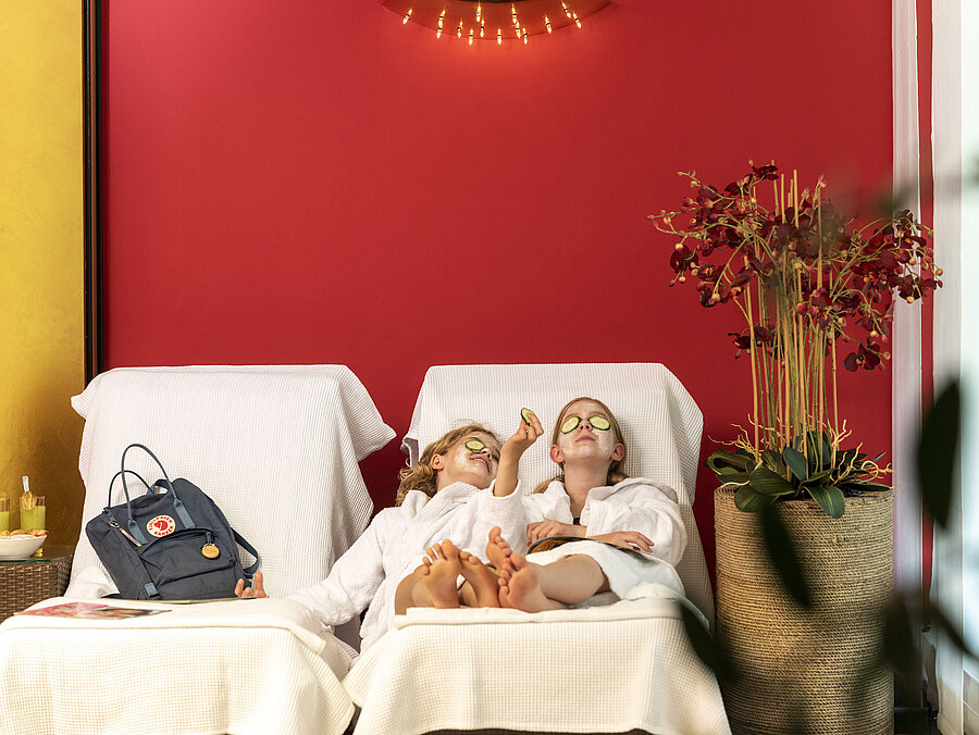 Two girls with facial masks and cucumber slices relax at the Maritim Hotel Spa, enjoying their treatment.