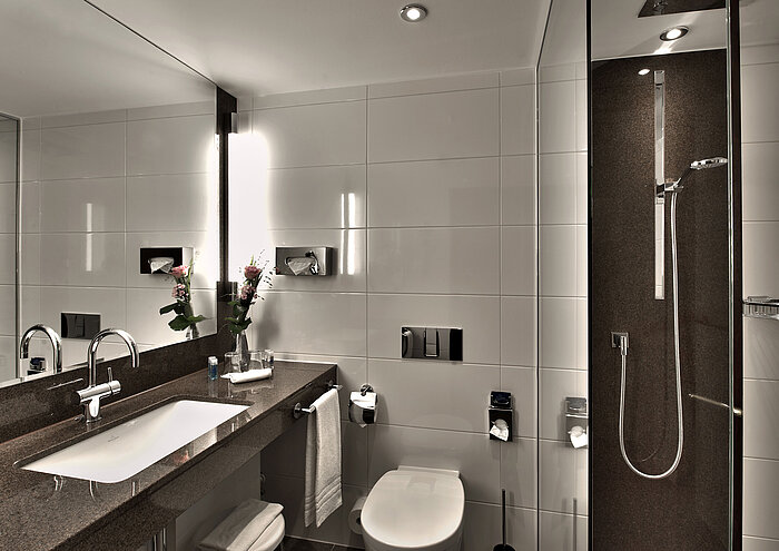 Modern bathroom at Maritim Hotel Cologne with bathtub, large mirror, and stylish lighting in neutral tones.