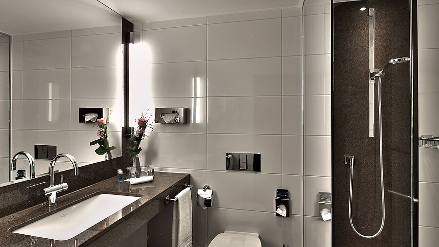 Modern bathroom at Maritim Hotel Cologne with bathtub, large mirror, and stylish lighting in neutral tones.