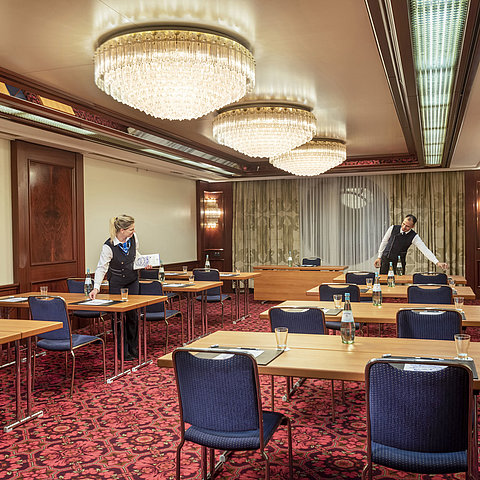 Salon Bonn at Maritim Cologne, staff preparing the room with tables, water bottles, and glasses for an event.