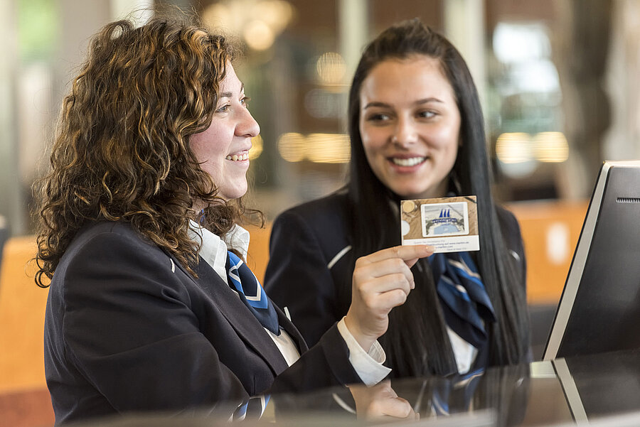 Smiling reception staff at Maritim Hotel Frankfurt presenting a room card.