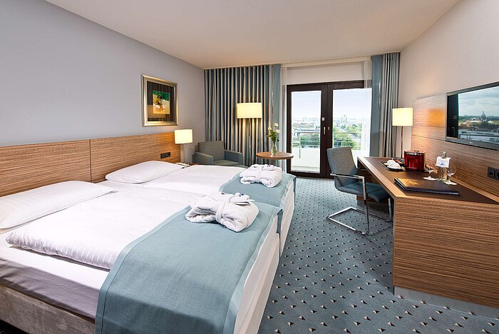 Superior room at Maritim Hotel Darmstadt featuring stylish design, desk, cozy seating area, and double bed with bathrobes.