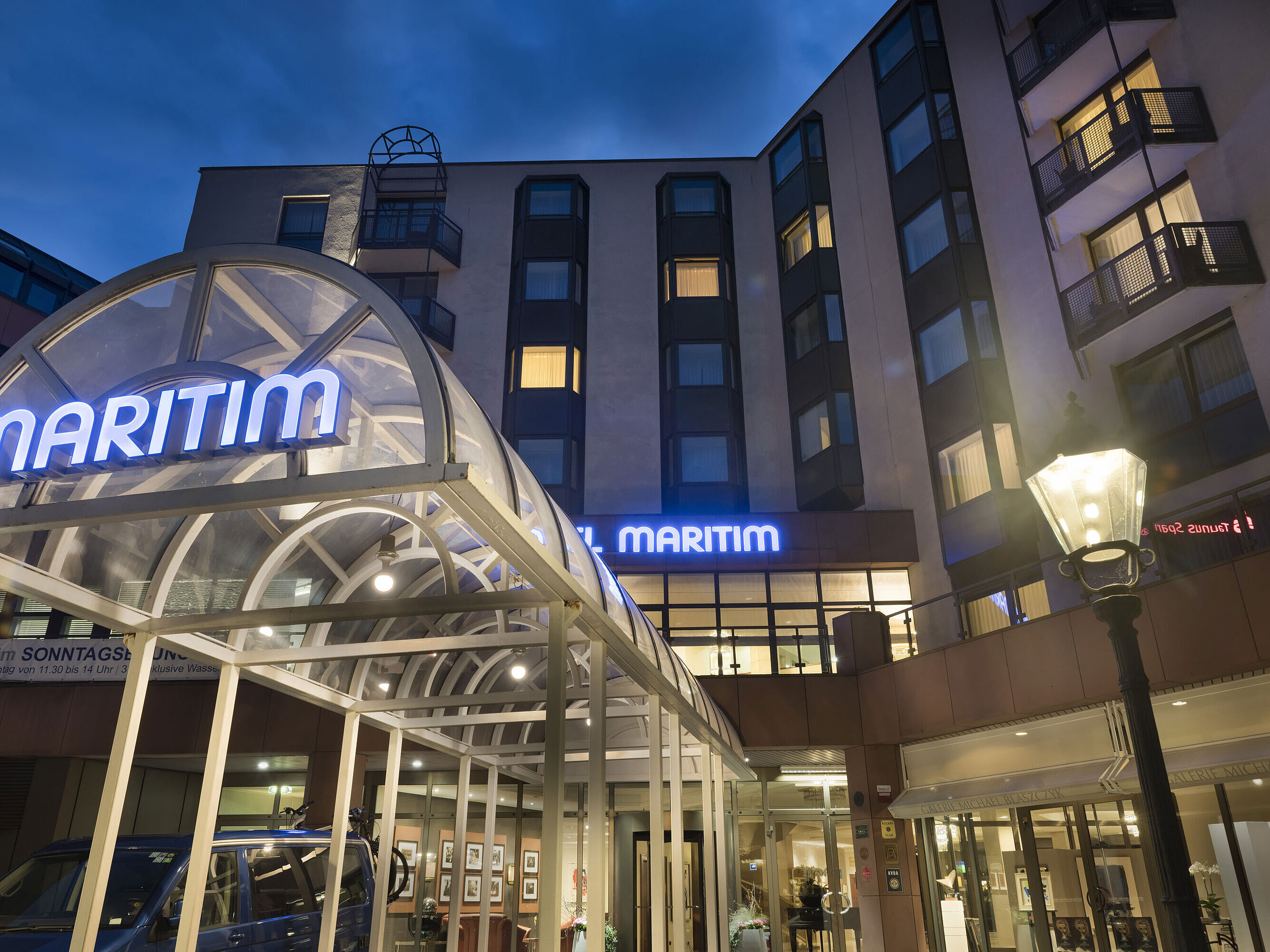 Detail view of the illuminated entrance area at Maritim Hotel Bad Homburg at night.