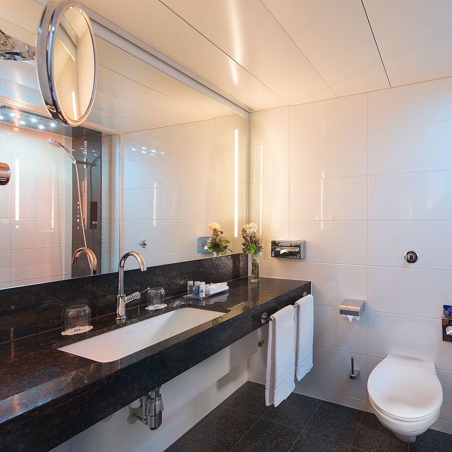 Spacious bathroom with shower, toilet, mirror and granite sink at the Maritim Hotel Stuttgart