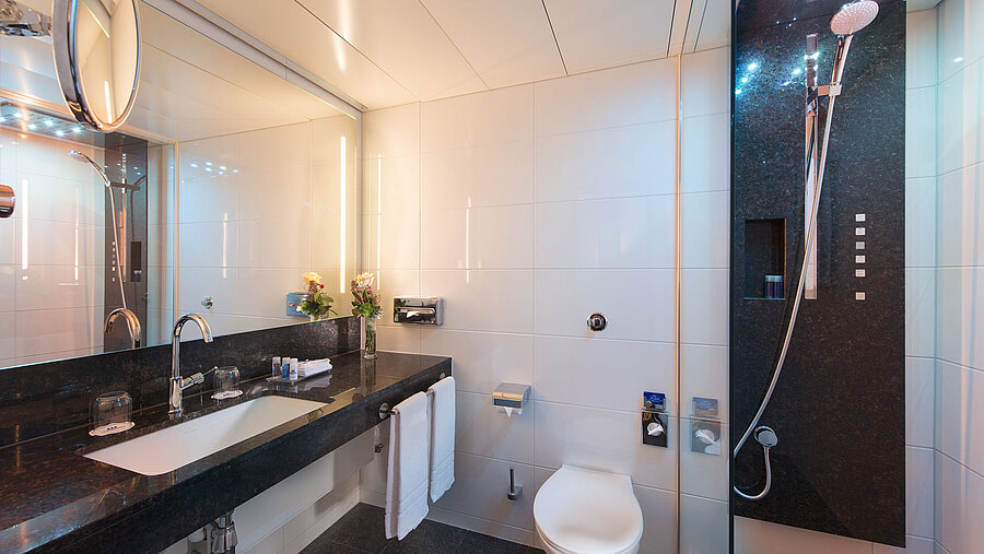 Spacious bathroom with shower, toilet, mirror and granite sink at the Maritim Hotel Stuttgart