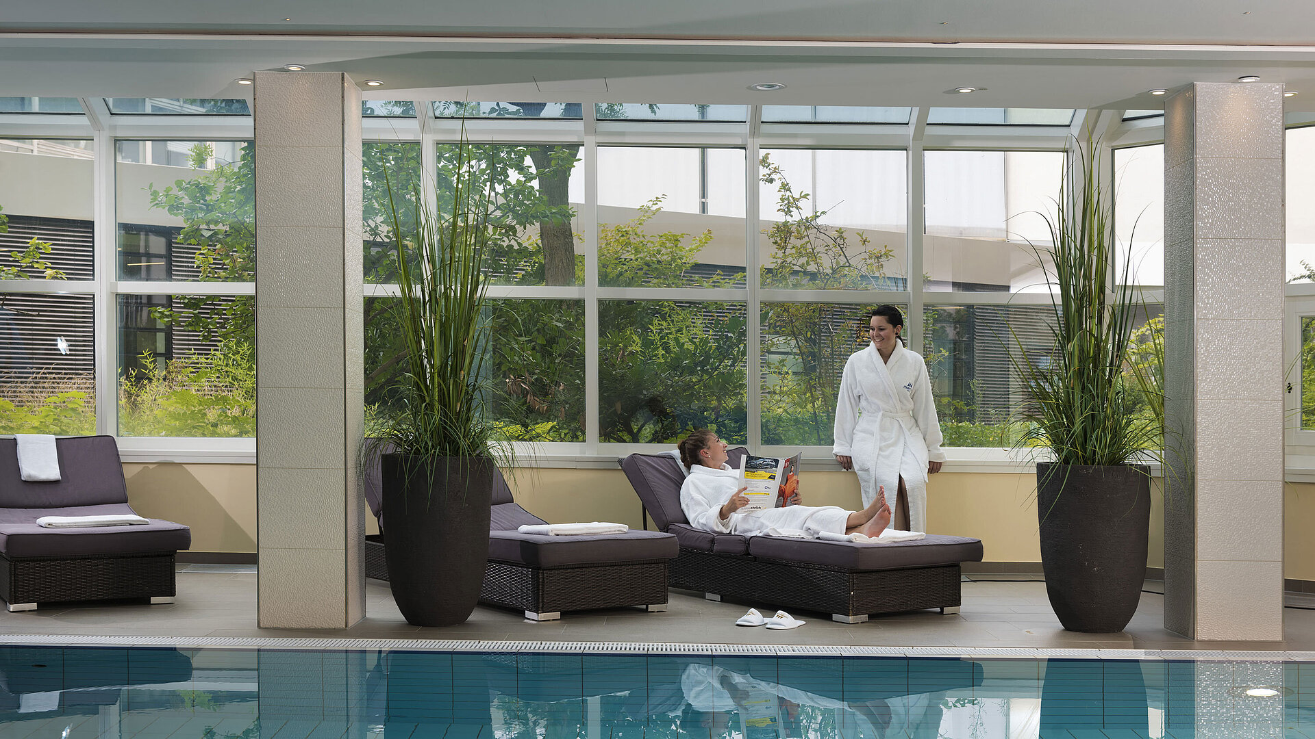 Relaxation area with pool and loungers at Maritim Hotel Würzburg – guests in bathrobes unwind.