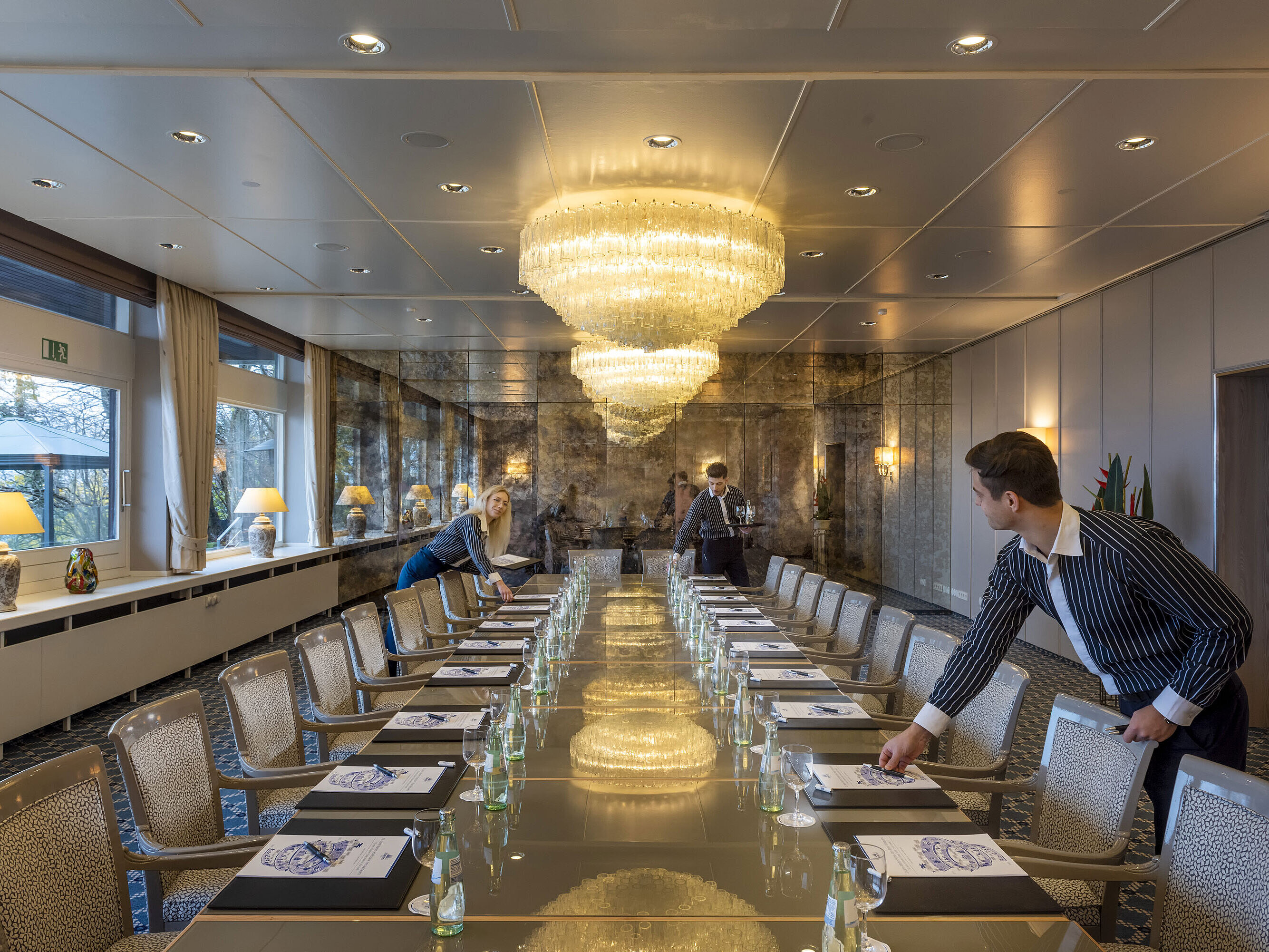 Salon Oslo in the Maritim Hotel Kiel, elegant conference room with chandeliers and a long row of tables, staff setting up the room.