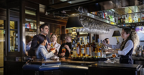 Guests enjoying cocktails and great vibes at the bar of Maritim Hotel Darmstadt. Friendly bar staff serving drinks.