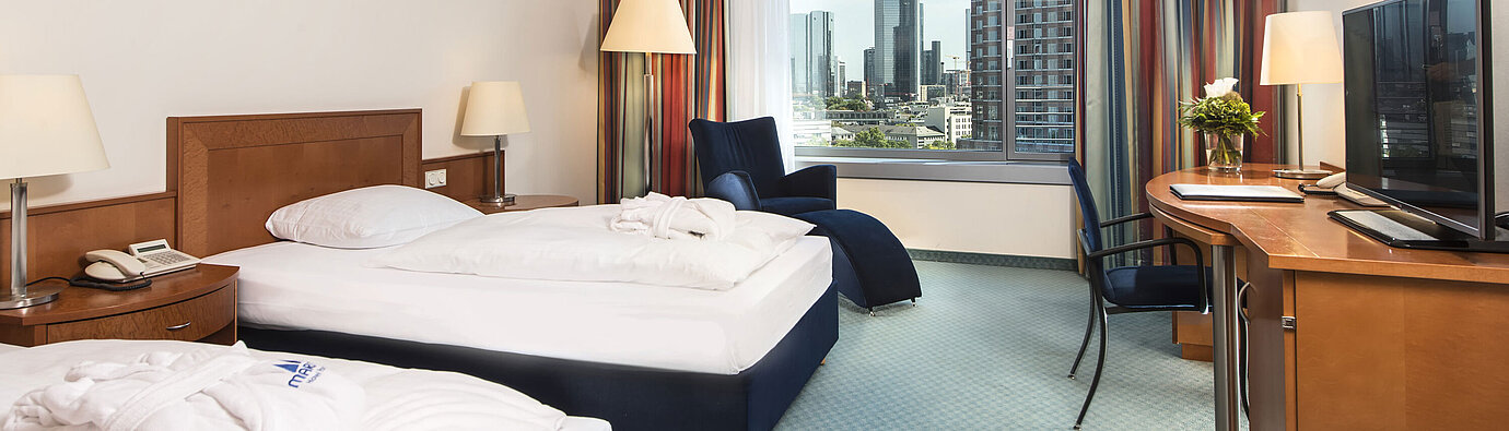 Superior room at Maritim Hotel Frankfurt with two single beds, desk, seating area, and stunning skyline view.