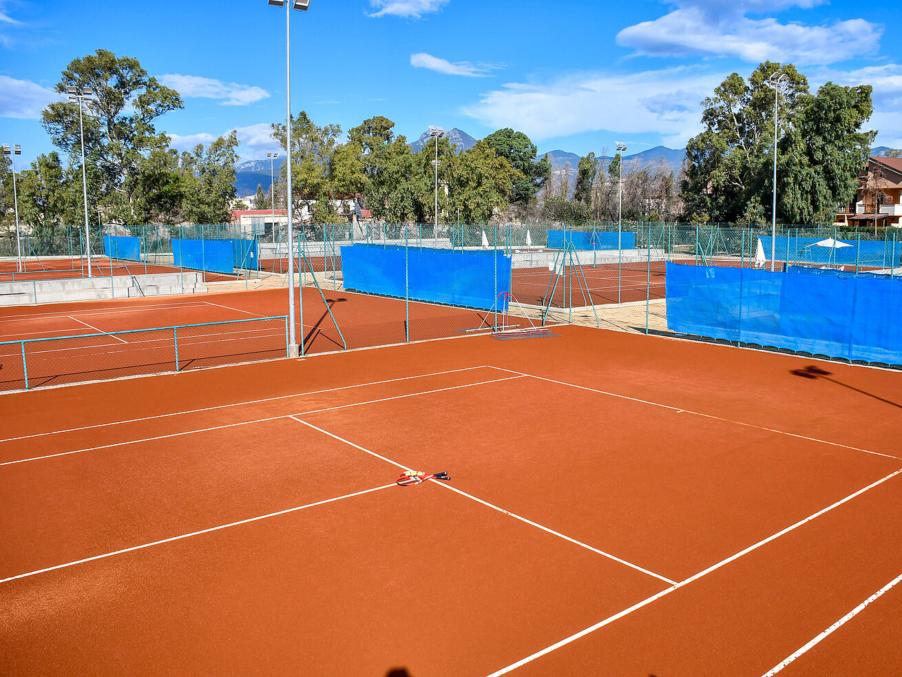 Red clay tennis courts at Maritim Resort Calabria under blue sky for sporty holiday activities