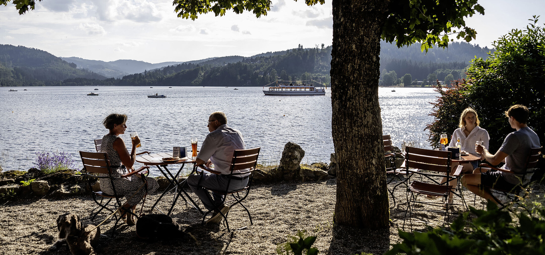 Guests relaxing in the beer garden of Maritim Hotel Titisee with lake and mountain view