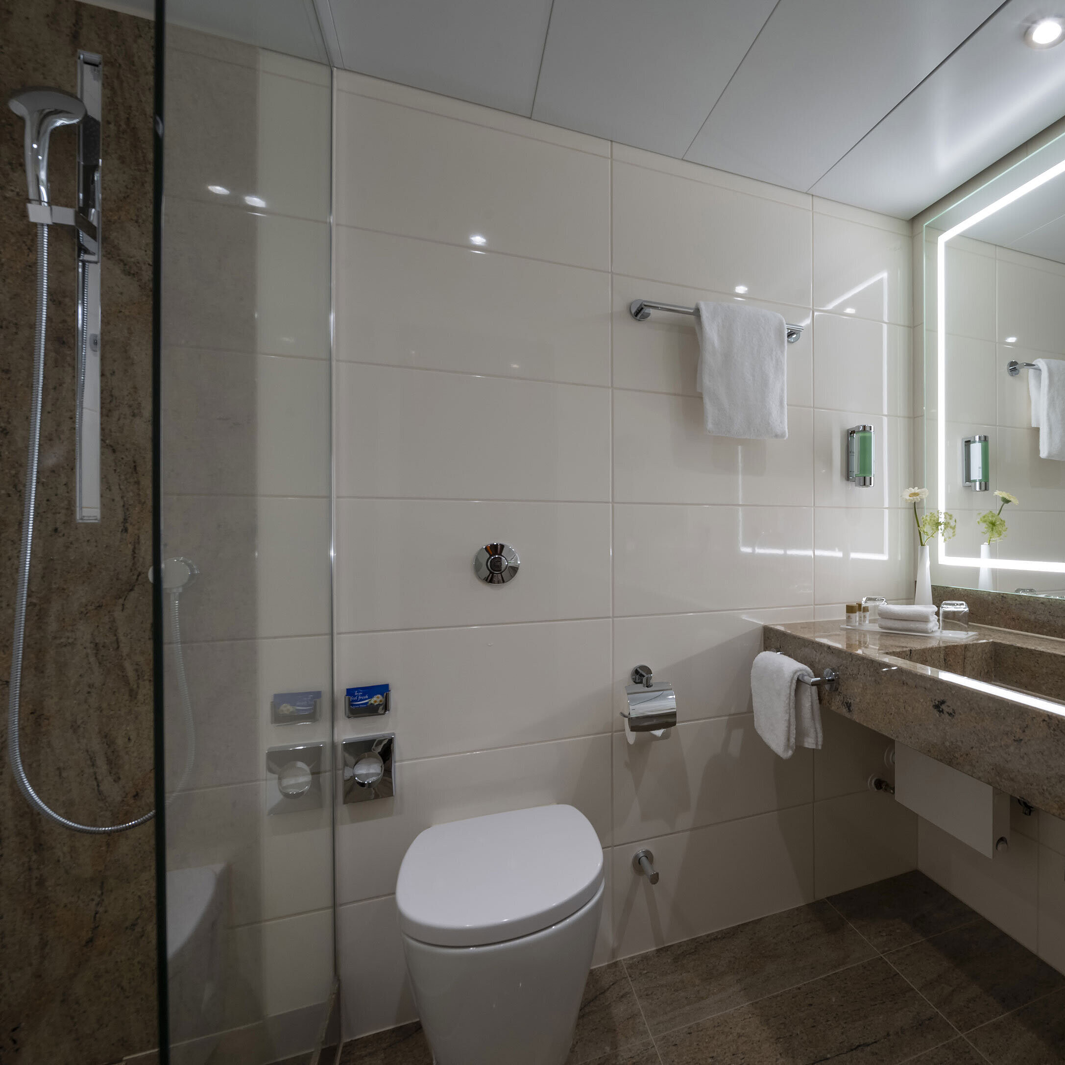 Modern bathroom at the Maritim Hotel Bremen with luxurious fixtures, large illuminated mirror, and walk-in shower.