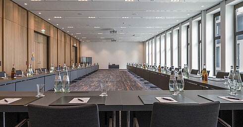 Meeting room at Maritim Hotel Ingolstadt with large windows, U-shape seating and conference materials.
