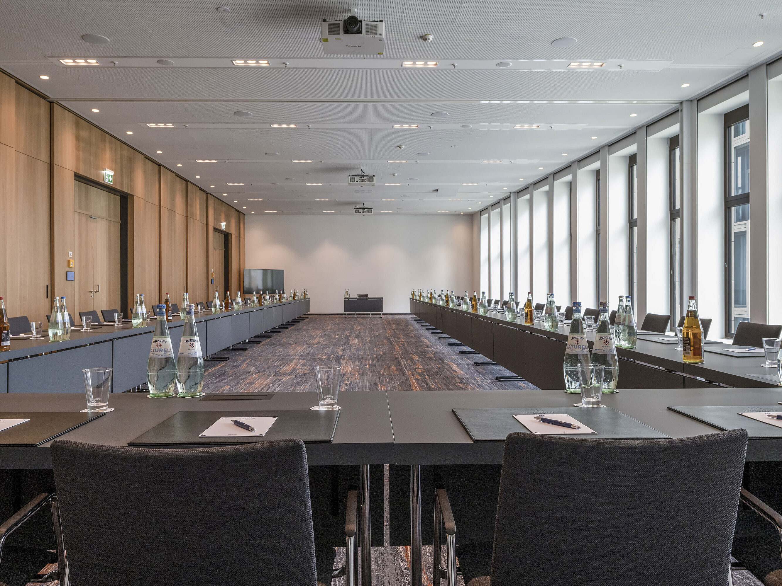 Meeting room at Maritim Hotel Ingolstadt with large windows, U-shape seating and conference materials.