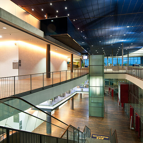 Modern, illuminated atrium in Maritim Hotel Dresden with escalators and glass architecture.
