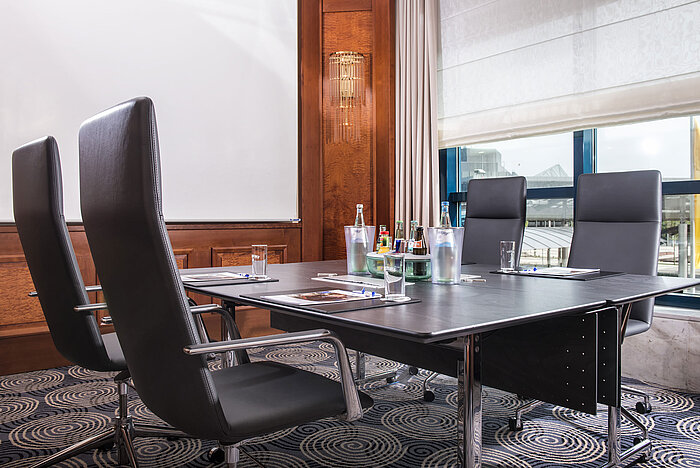 Modern meeting room with a large table, leather chairs, and natural light at Maritim Hotel Hannover.