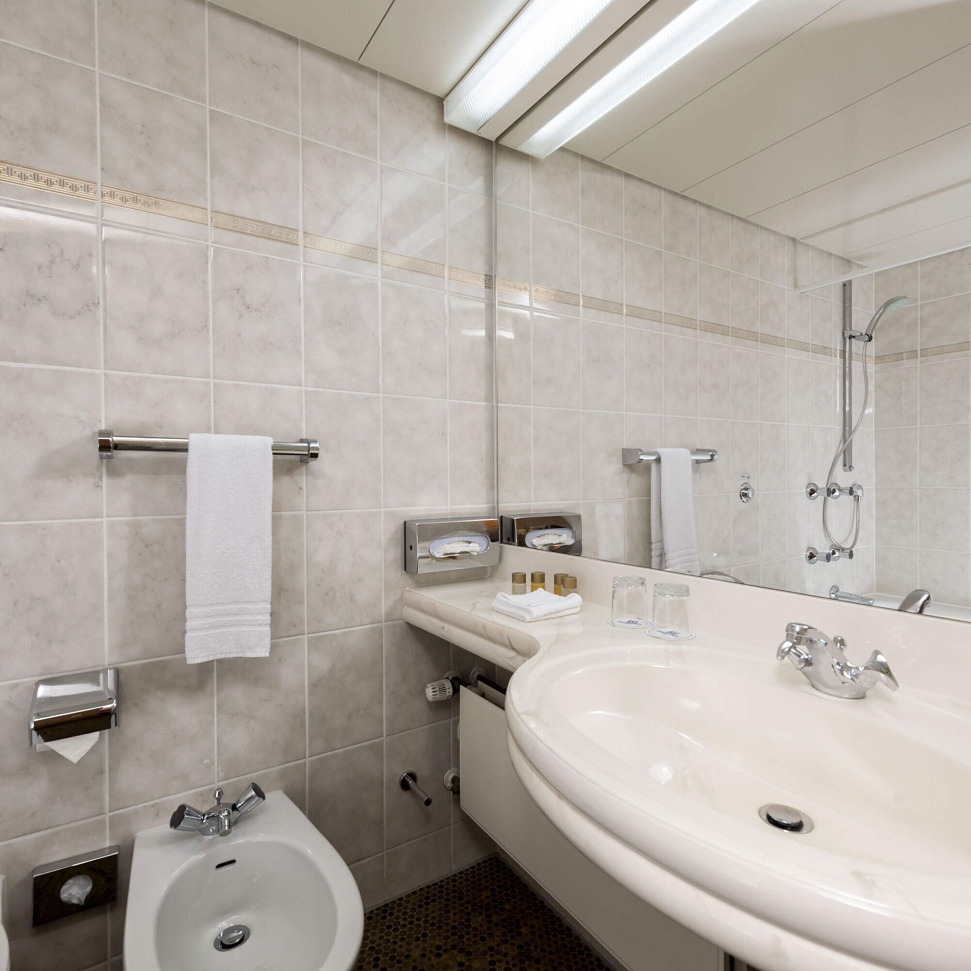 Bright bathroom with bidet, sink, mirror and fresh towels at Maritim Hotel Bad Wildungen