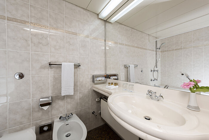 Bright bathroom with bidet, sink, mirror and fresh towels at Maritim Hotel Bad Wildungen