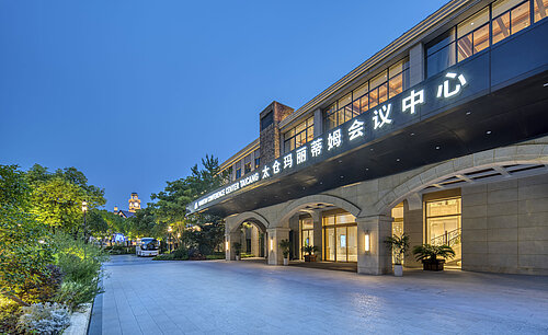 Illuminated entrance of the Maritim Conference Center Taicang at dusk, framed by greenery and modern design