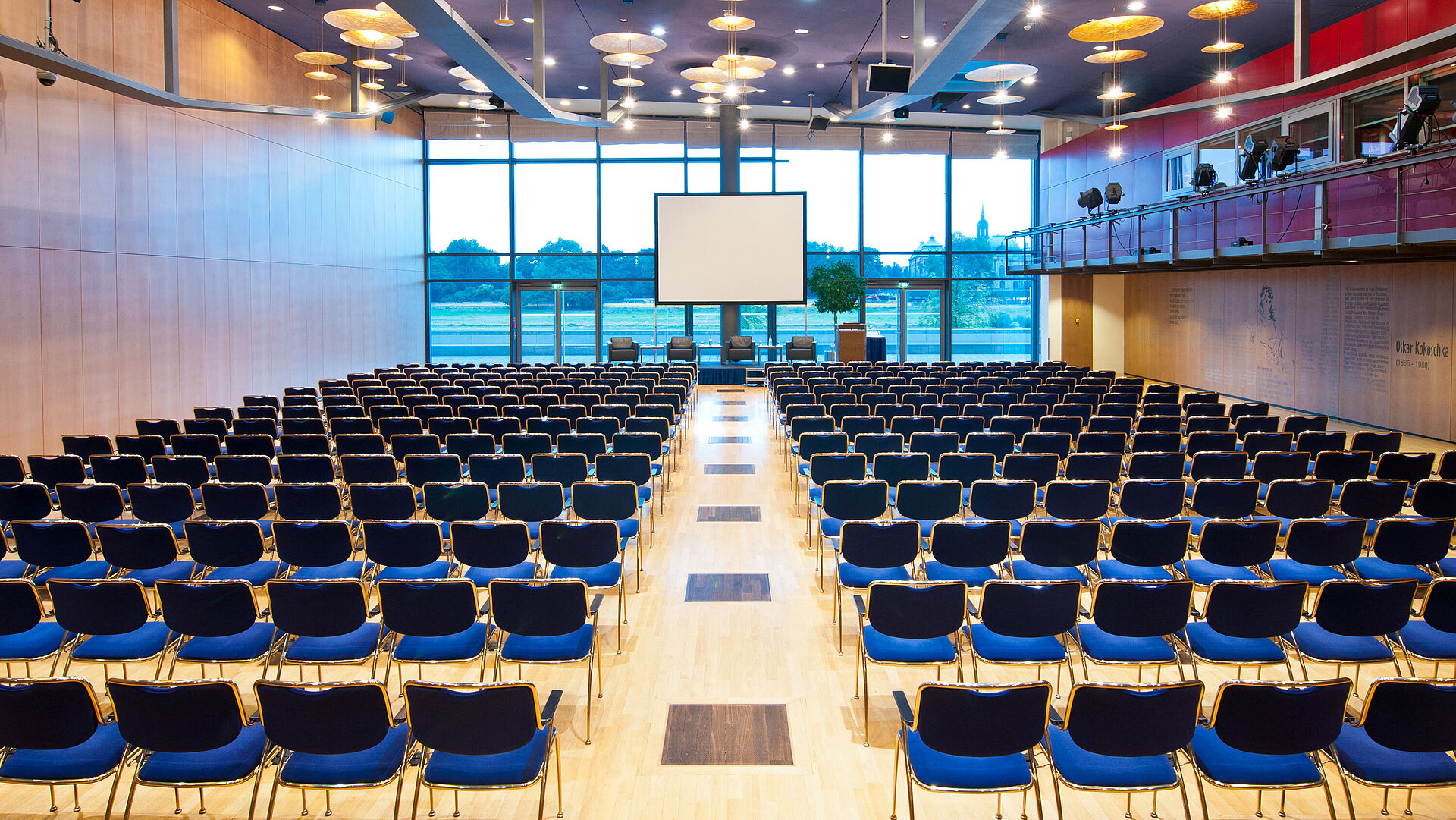 Large conference hall in Maritim Hotel Dresden with rows of blue chairs and a view of the Elbe River.