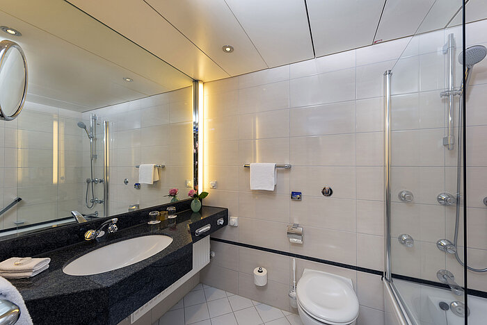 Modern bathroom at Maritim Hotel Frankfurt with large mirror, stylish sink, and shower-bathtub.